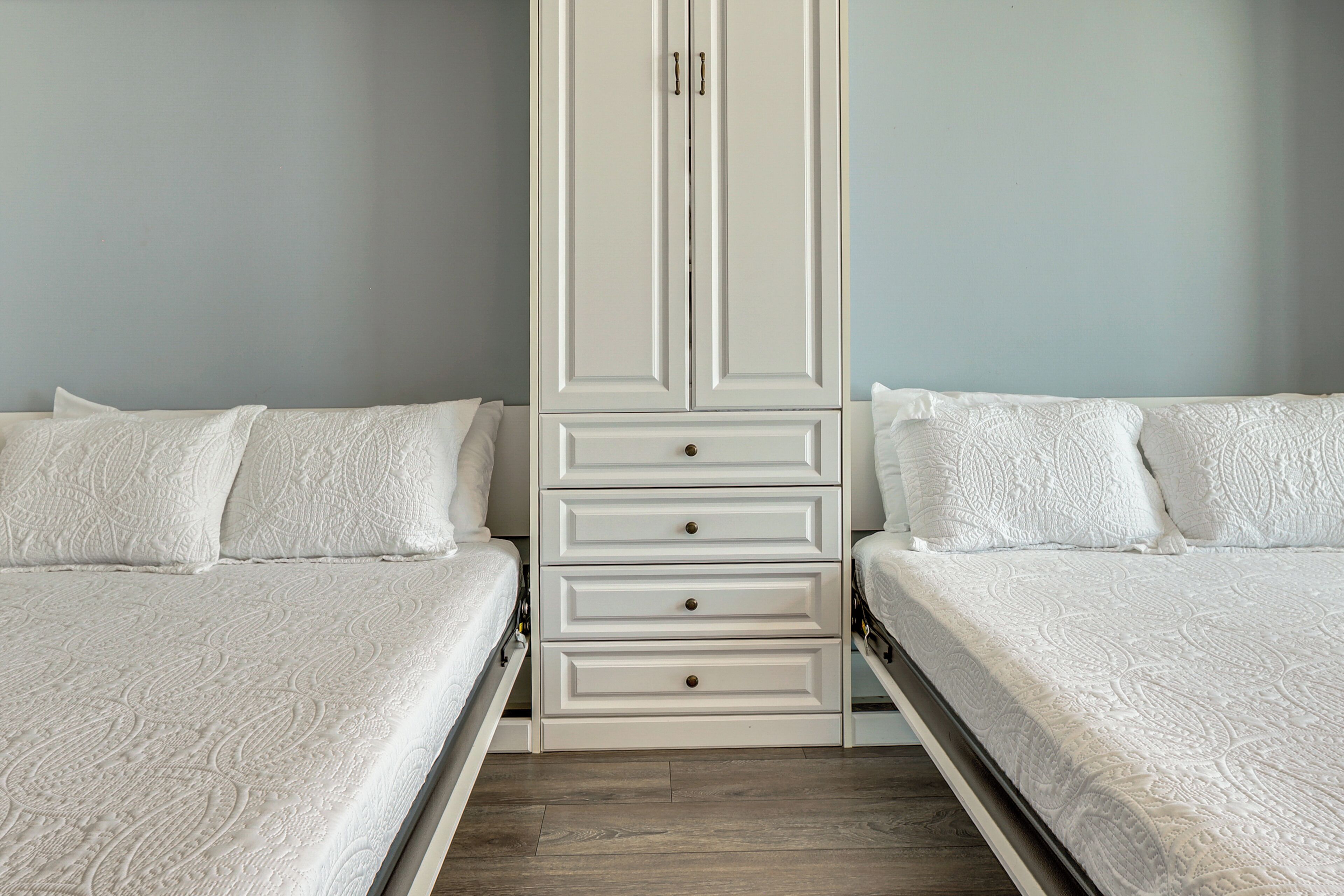 A bedroom with two beds, a wardrobe, and a wooden floor.