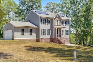 A two-story house with a garage, a covered porch, and a staircase leading to the main entrance. - On 4+ Acres! Modern Home w/ Lake Access in Orange (Orange)