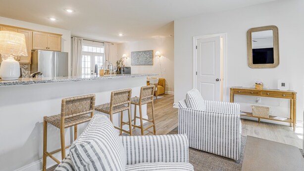 A modern kitchen with a refrigerator, stove, and dining area with chairs and a table.