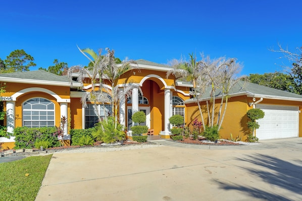 A two-story house with a yellow facade, large windows, and a garage.