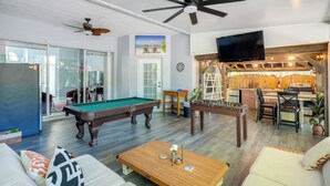 A living room with a pool table, sofa, coffee table, and a TV mounted on the wall. - Games, Outdoor Kitchen: Port St Lucie Family Home (Port Saint Lucie)