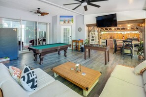 A living room with a pool table, sofa, coffee table, and a TV mounted on the wall. - Games, Outdoor Kitchen: Port St Lucie Family Home (Port Saint Lucie)