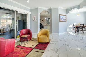 A modern living room with a red sofa, yellow armchair, and a dining area with a table and chairs. - Games, Outdoor Kitchen: Port St Lucie Family Home (Port Saint Lucie)