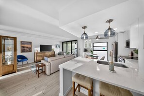 A modern kitchen with a large island, built-in appliances, and pendant lighting. - Top-Floor Condo Sunrise River View Private Lanai Walking Distance to Restaurants (Marco Island)