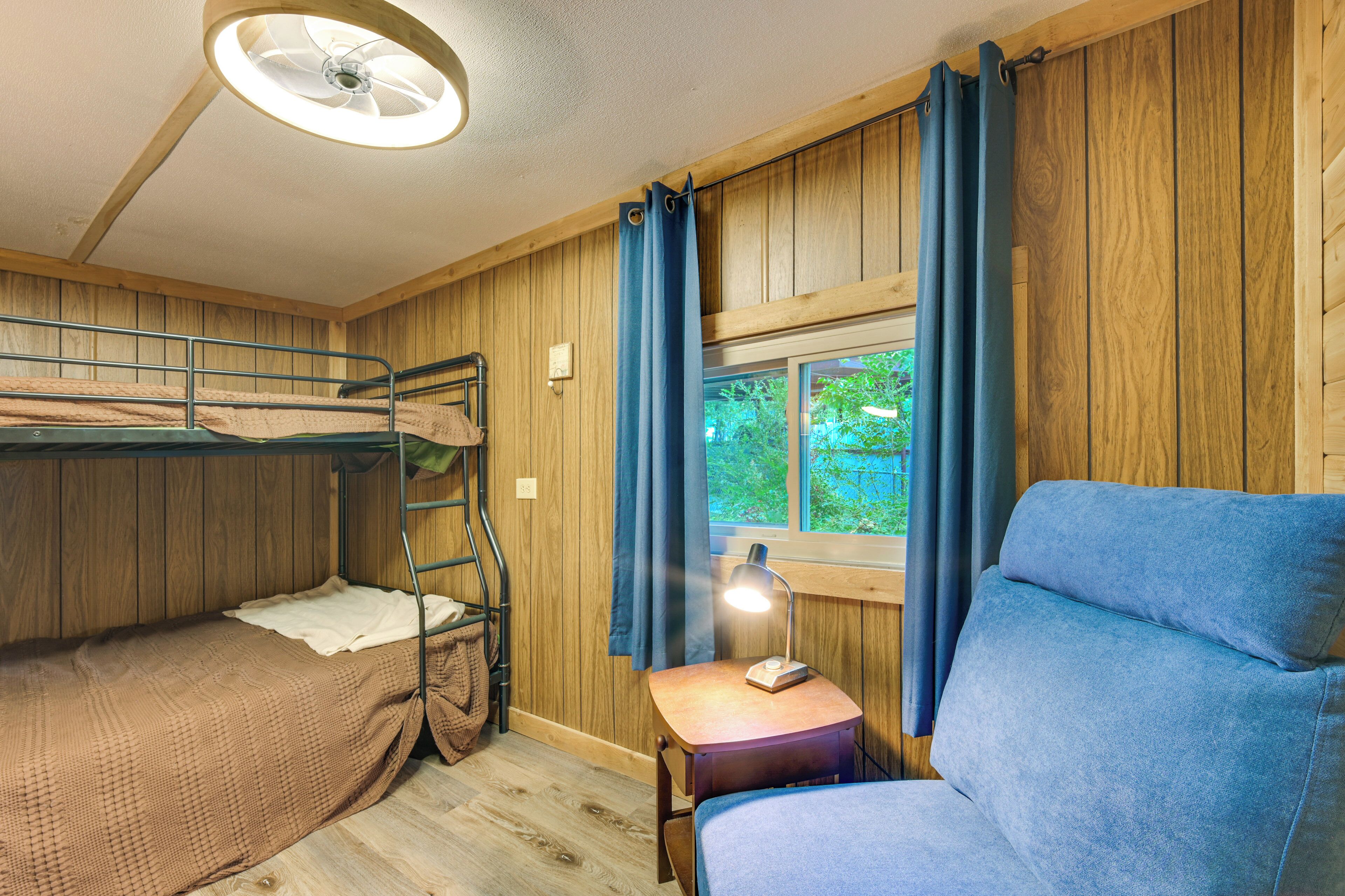 A room with bunk beds, a desk with a lamp, and a window with curtains.