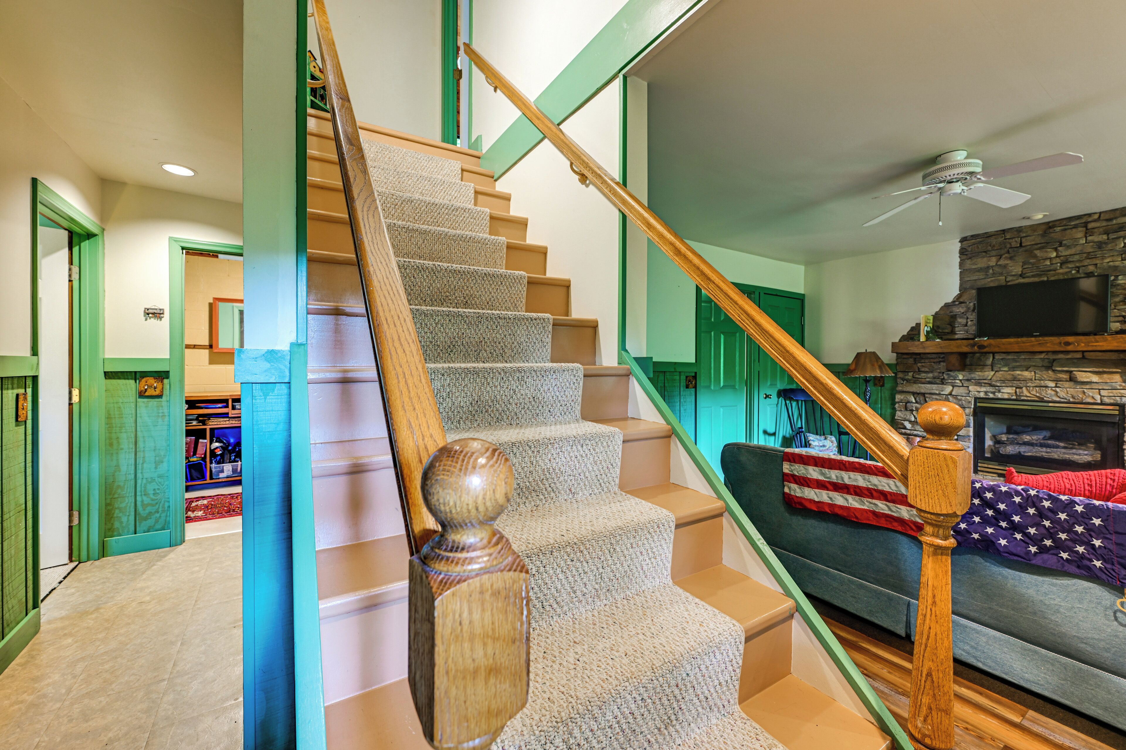 Un escalier avec des balustrades en bois, des marches recouvertes de moquette et un cadre de porte vert.