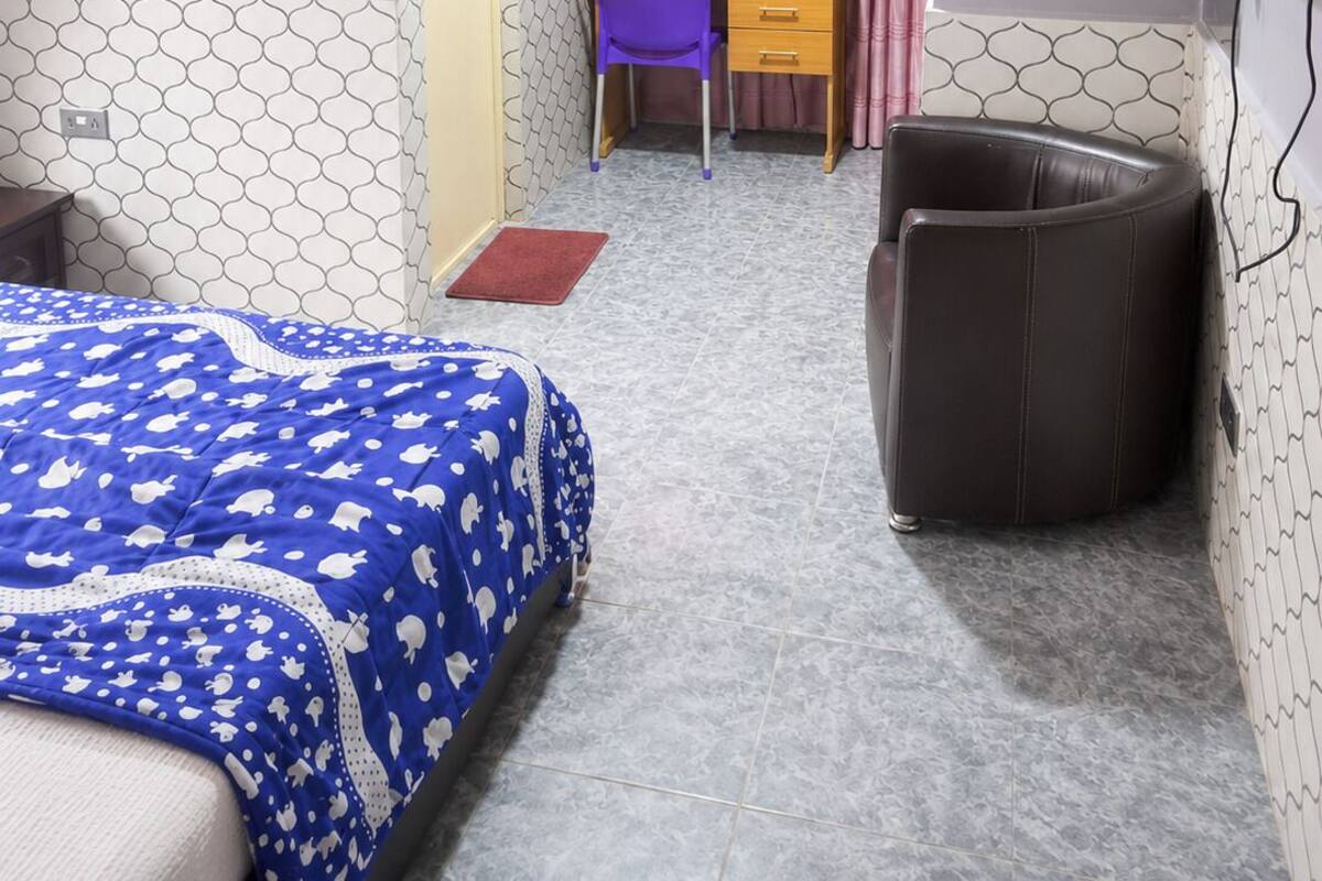Un dormitorio con cama, escritorio, silla, televisor y ventilador de techo.