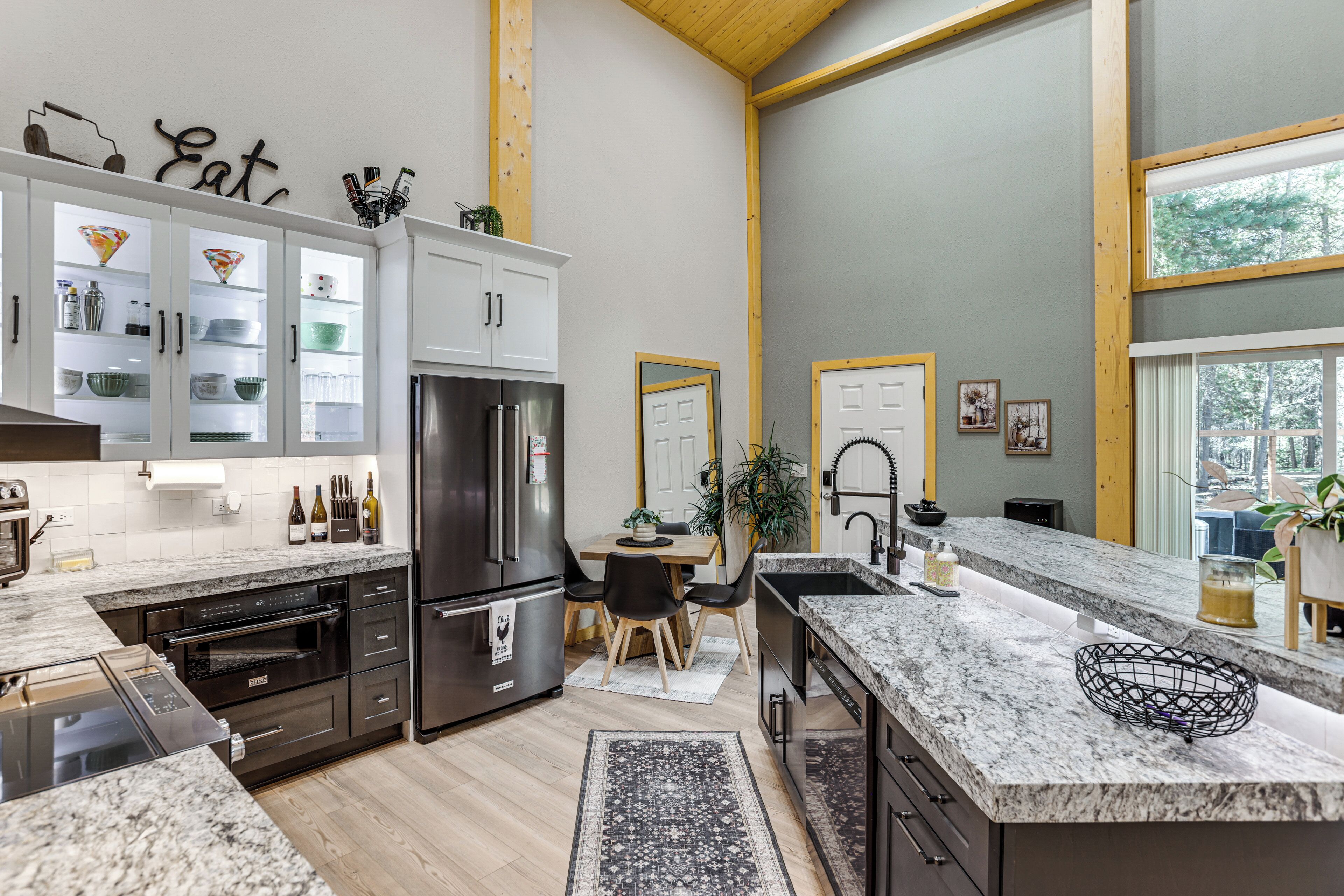 Una cucina moderna con elettrodomestici integrati, un'area pranzo e ampie finestre.