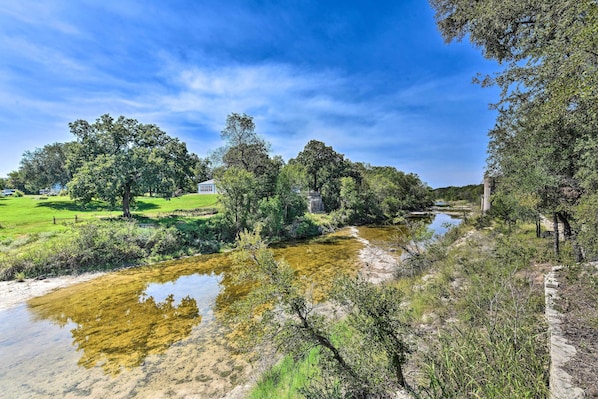 Un río serpenteando por un paisaje exuberante con árboles y un campo cubierto de hierba.