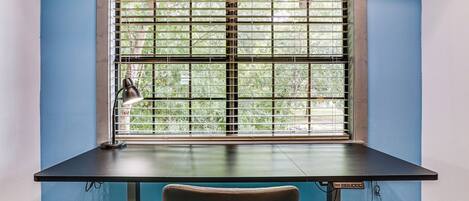 A desk with a lamp, a chair, and a window with blinds.