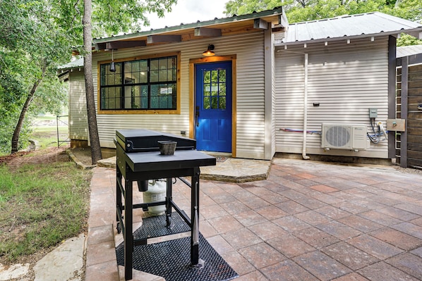 A small building with a blue door, a window, and an air conditioning unit.