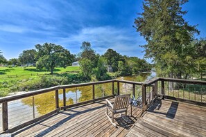 A wooden deck with a bench overlooking a river and a grassy area with trees. - Paluxy Riverfront Couples Studio on Over 2 Acres! (Glen Rose)