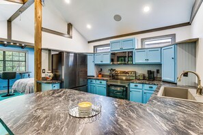 A modern kitchen with blue cabinets, a marble countertop, and stainless steel appliances.