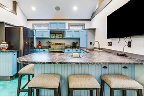 A kitchen with blue cabinets, a marble island, and bar stools. - Paluxy Riverfront Couples Studio on Over 2 Acres! (Glen Rose)