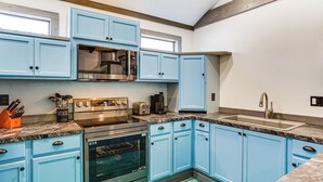 A kitchen with blue cabinets, stainless steel appliances, and a marble countertop. - Paluxy Riverfront Couples Studio on Over 2 Acres! (Glen Rose)
