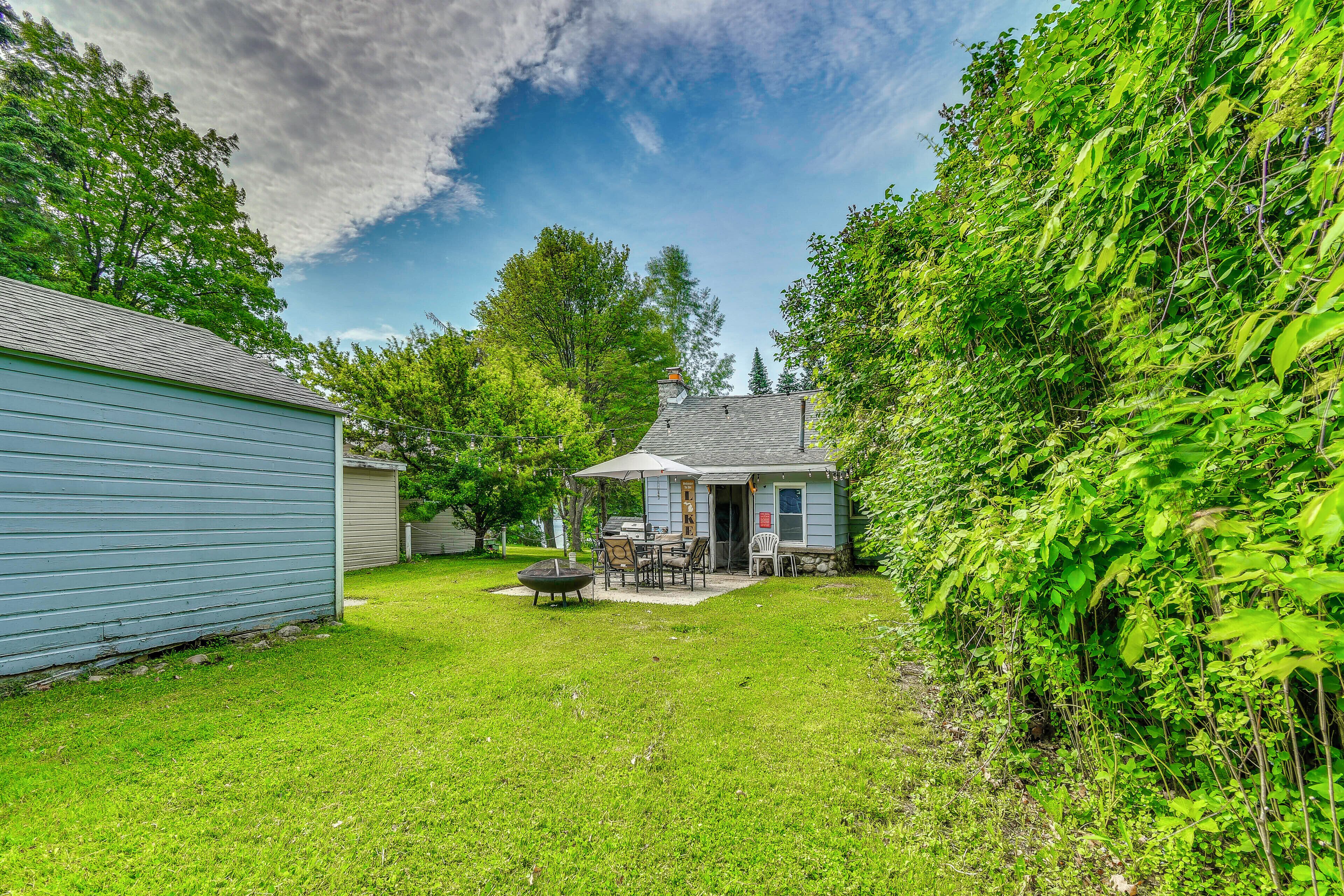 A backyard with a patio, a small shed, and a house.