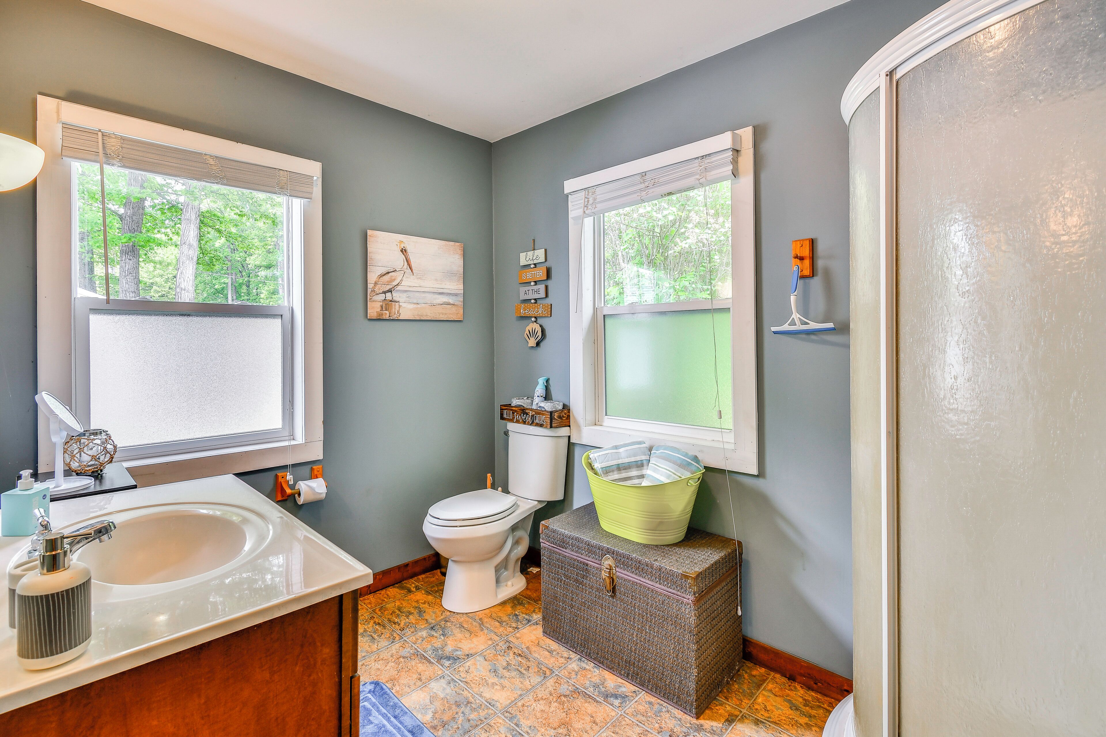 A bathroom with a sink, toilet, and a window with a view of trees.