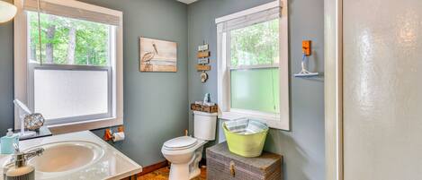 A bathroom with a sink, toilet, and a window with a view of trees.