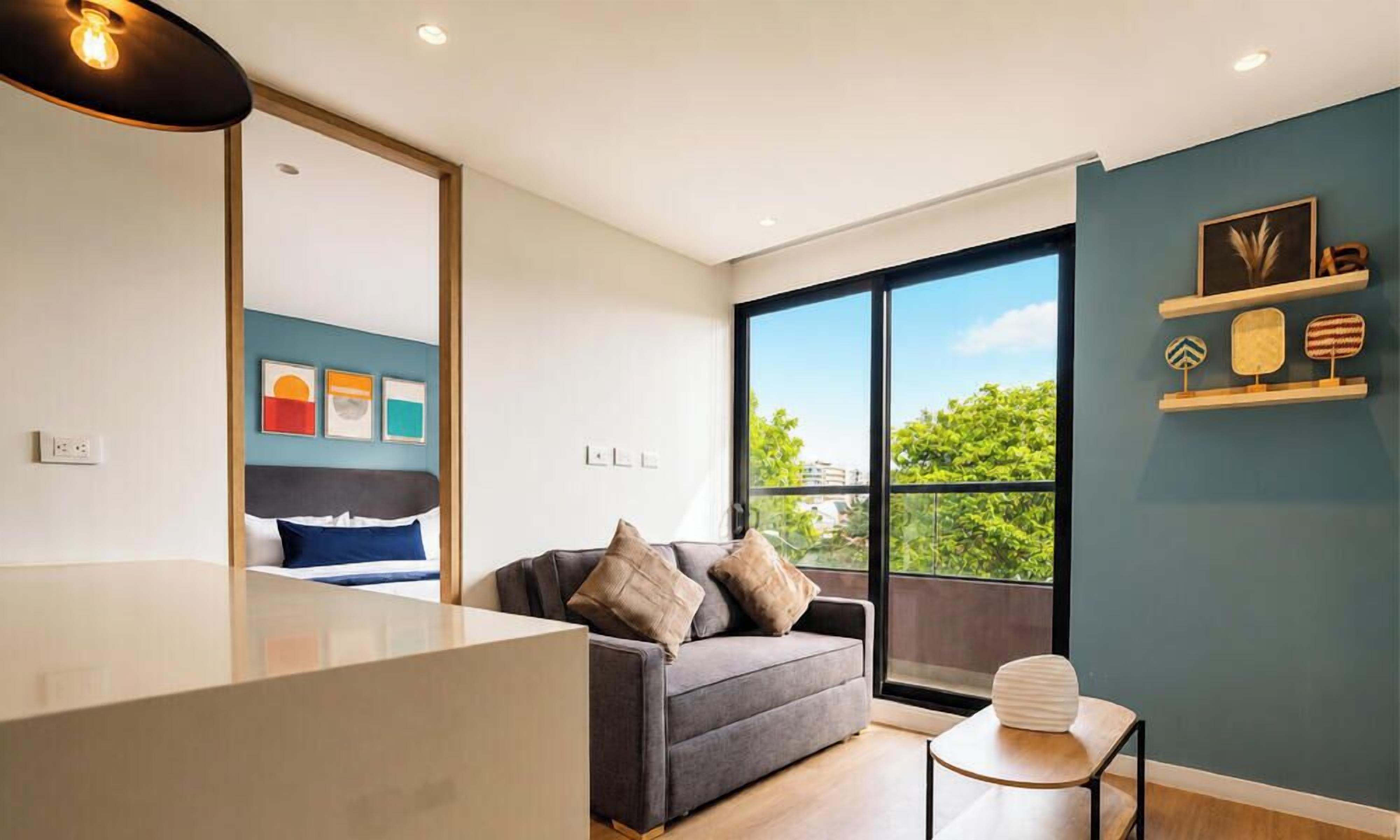 Un salón moderno con un sofá, una mesita y un ventanal grande que ofrece vistas a zonas verdes.