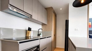Cocina moderna con electrodomésticos de acero inoxidable, horno empotrado y refrigerador negro.