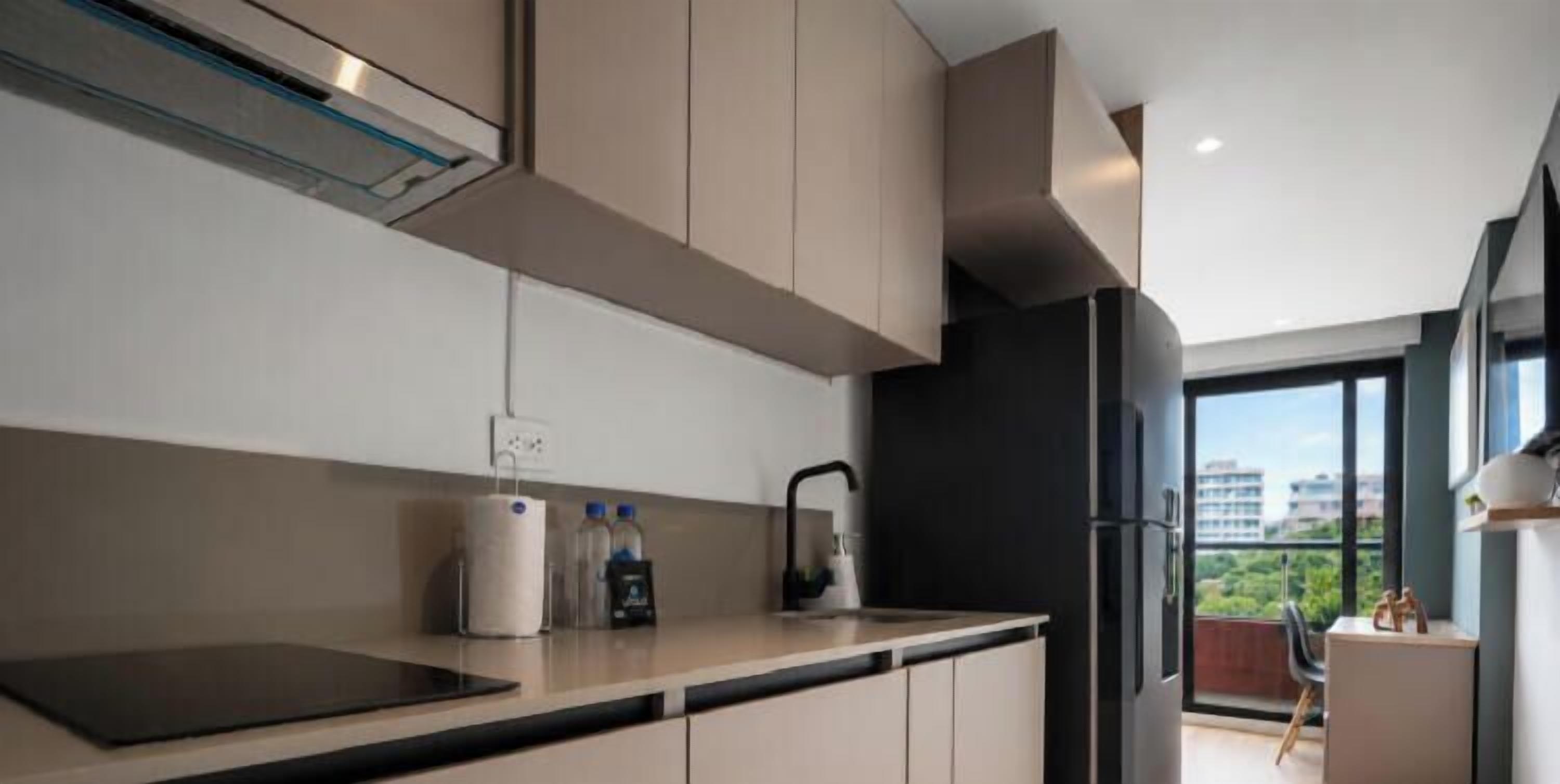 Een moderne keuken met een inbouwfornuis, een koelkast en een raam met uitzicht op een balkon.