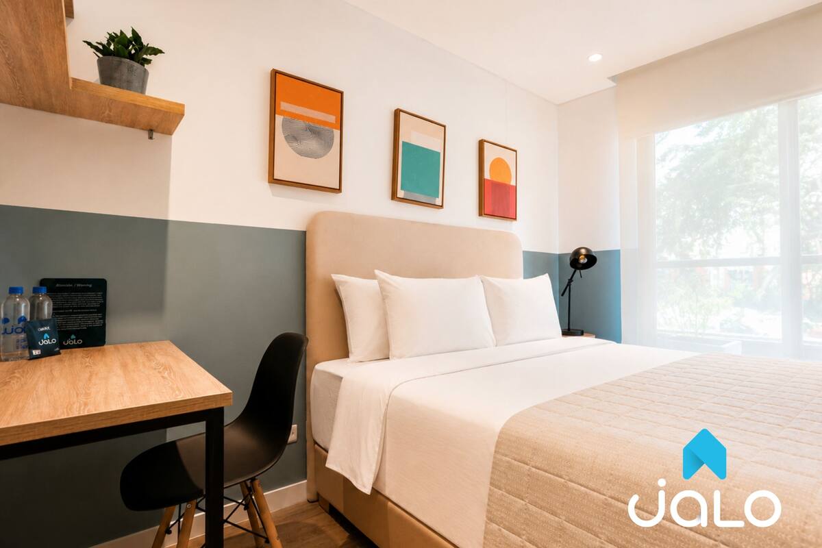 Una habitación de hotel con cama, escritorio, silla y ventana.