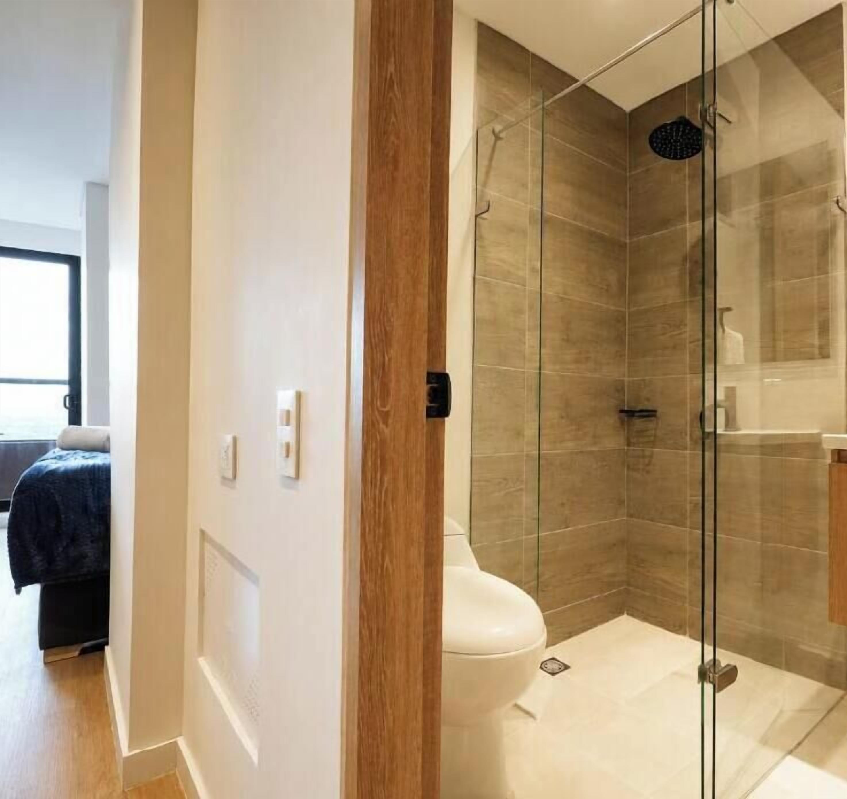 A modern bathroom with a glass-enclosed shower, a toilet, and a sink.