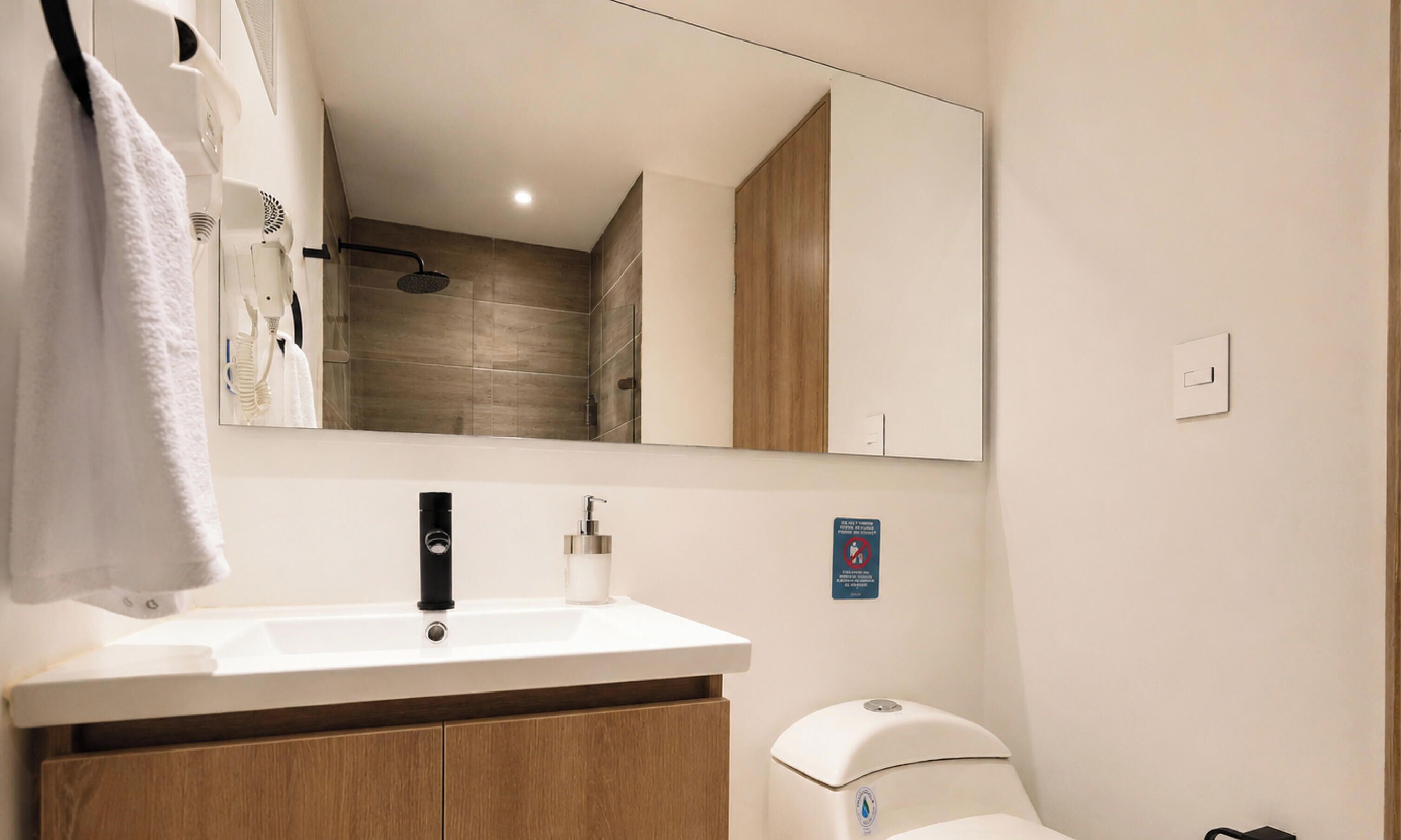Une salle de bain moderne avec un lavabo blanc, des meubles en bois, un miroir et des toilettes.