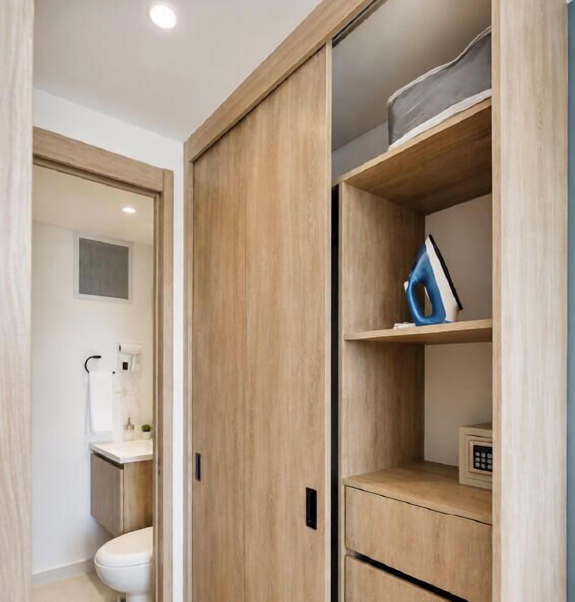 Une salle de bain moderne équipée de toilettes, d’un lavabo et d’une armoire en bois avec des étagères.