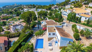 Zona residencial com piscina, casas com telhados de barro e vista para o mar.