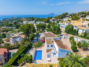 Ein Wohngebiet mit Swimmingpool, Häusern mit roten Ziegeldächern und Blick auf das Meer.