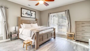 Un dormitorio con una cama de madera, un ventilador de techo, una mesita de noche, un armario de madera y una ventana con persianas.