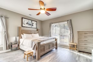 A bedroom with a wooden bed, a ceiling fan, a bedside table, a nightstand, a window with blinds, and a wooden wardrobe. - Guyton Home w Pool, Theater & Arcade! (Guyton)