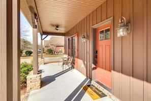 A covered porch with a red door, a bench, and a doormat. - Guyton Home w Pool, Theater & Arcade! (Guyton)