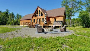 Een ruime houten lodge met een terras, buitenmeubels en een overdekt gedeelte.