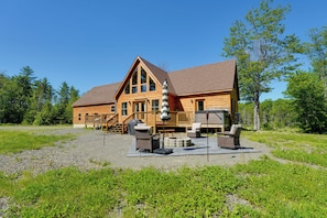 A large wooden lodge with a deck, outdoor seating, and a covered area.