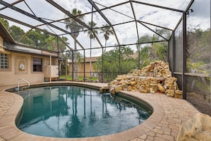 A swimming pool with a stone wall and a metal roof structure. - Dogs Welcome! Family-friendly Gem in Lehigh Acres (Lehigh Acres)