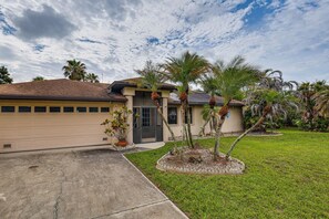 A single-story house with a garage, a front lawn, and palm trees.