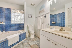 A bathroom with a bathtub, toilet, sink, and mirror. - Dogs Welcome! Family-friendly Gem in Lehigh Acres (Lehigh Acres)