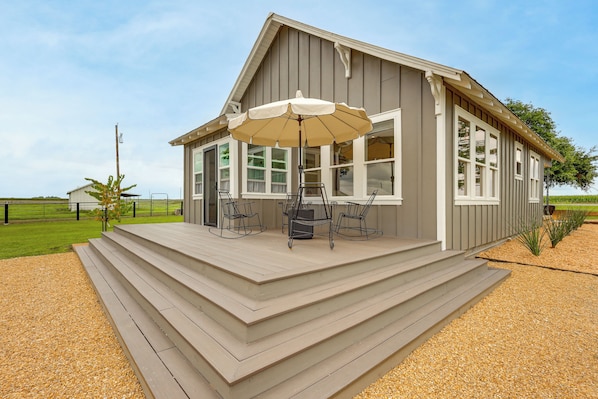 A house with a porch, a table with chairs, and an umbrella.