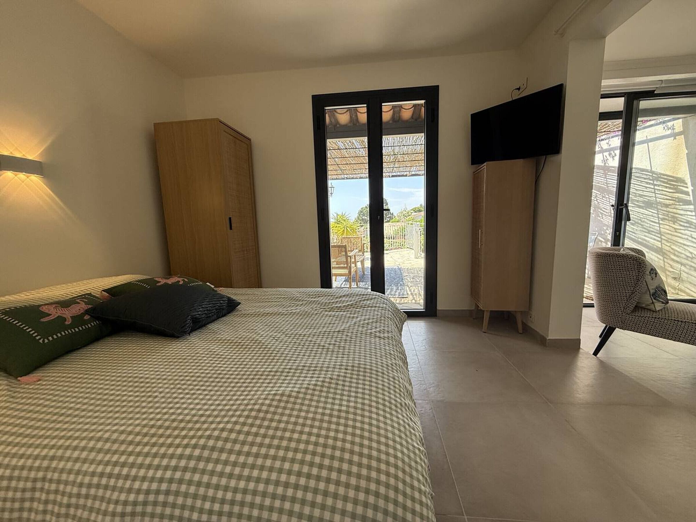 A bedroom with a bed, a wardrobe, a TV, and a chair.