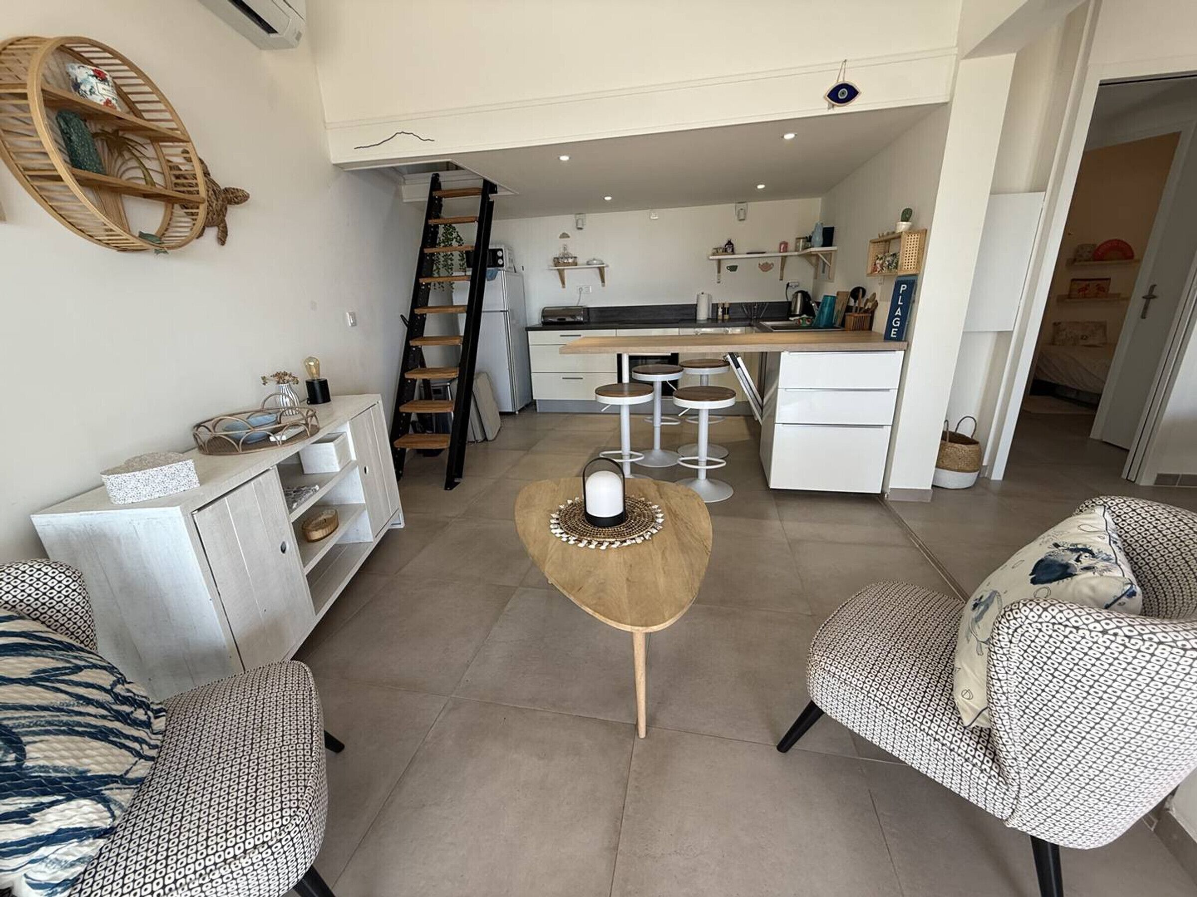 A modern living room with a sofa, a coffee table, and a kitchen area with a counter and stools.
