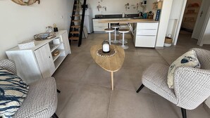 Una sala moderna con un sofá, una mesa de centro y una cocina con mostrador y taburetes.