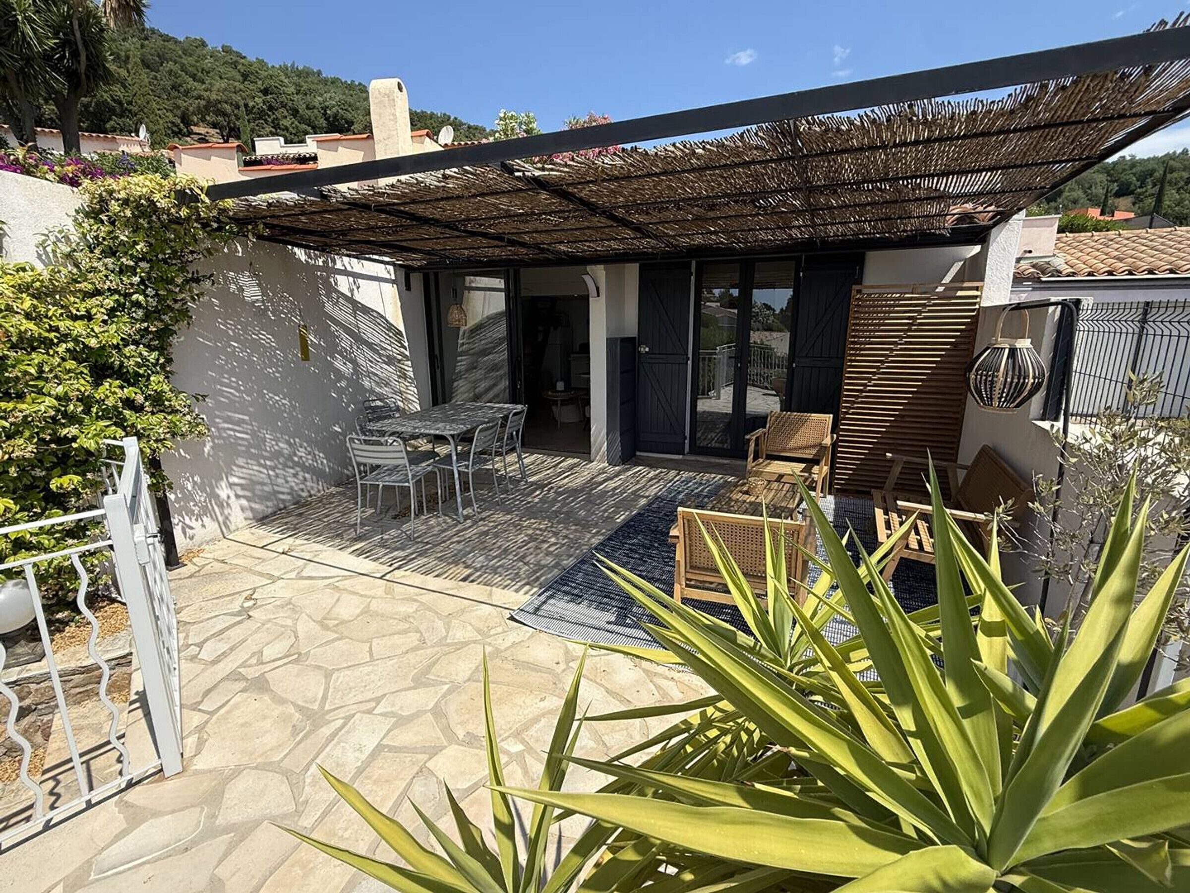 A patio with a table and chairs, a pergola, and a view of the surrounding area.