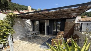 Un patio con mesa y sillas, una pérgola y vistas del entorno.