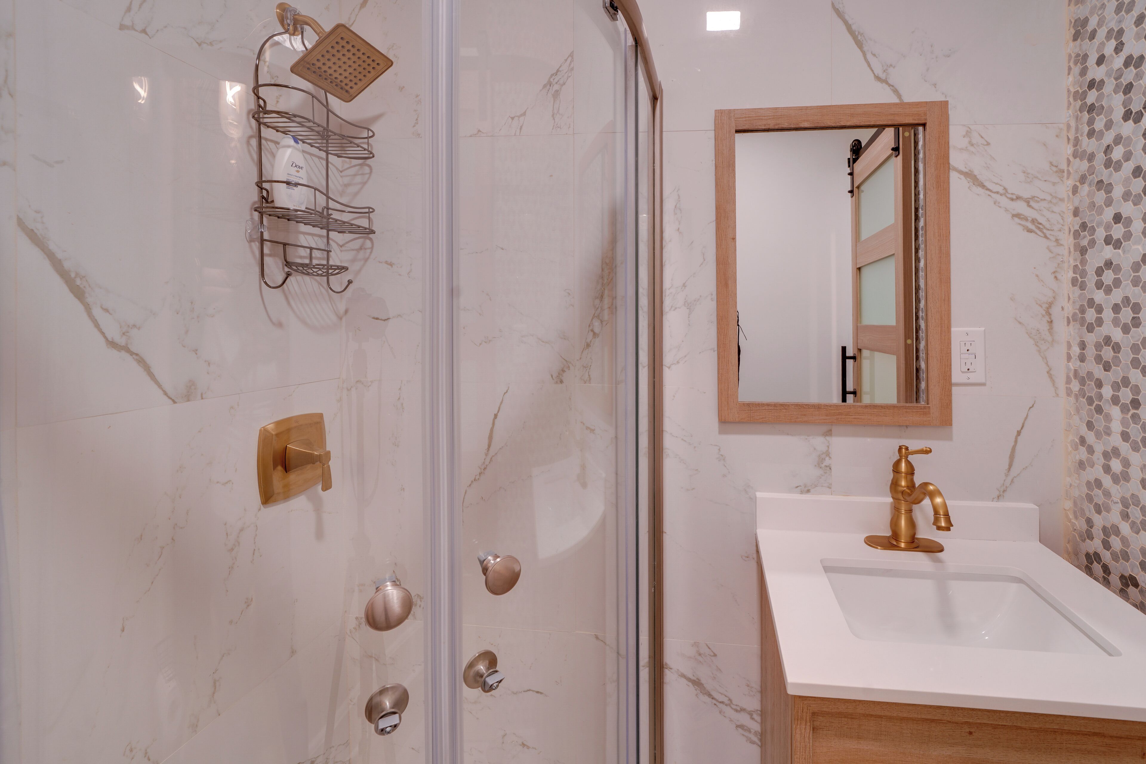 A bathroom with a shower, sink, mirror, and towel rack.