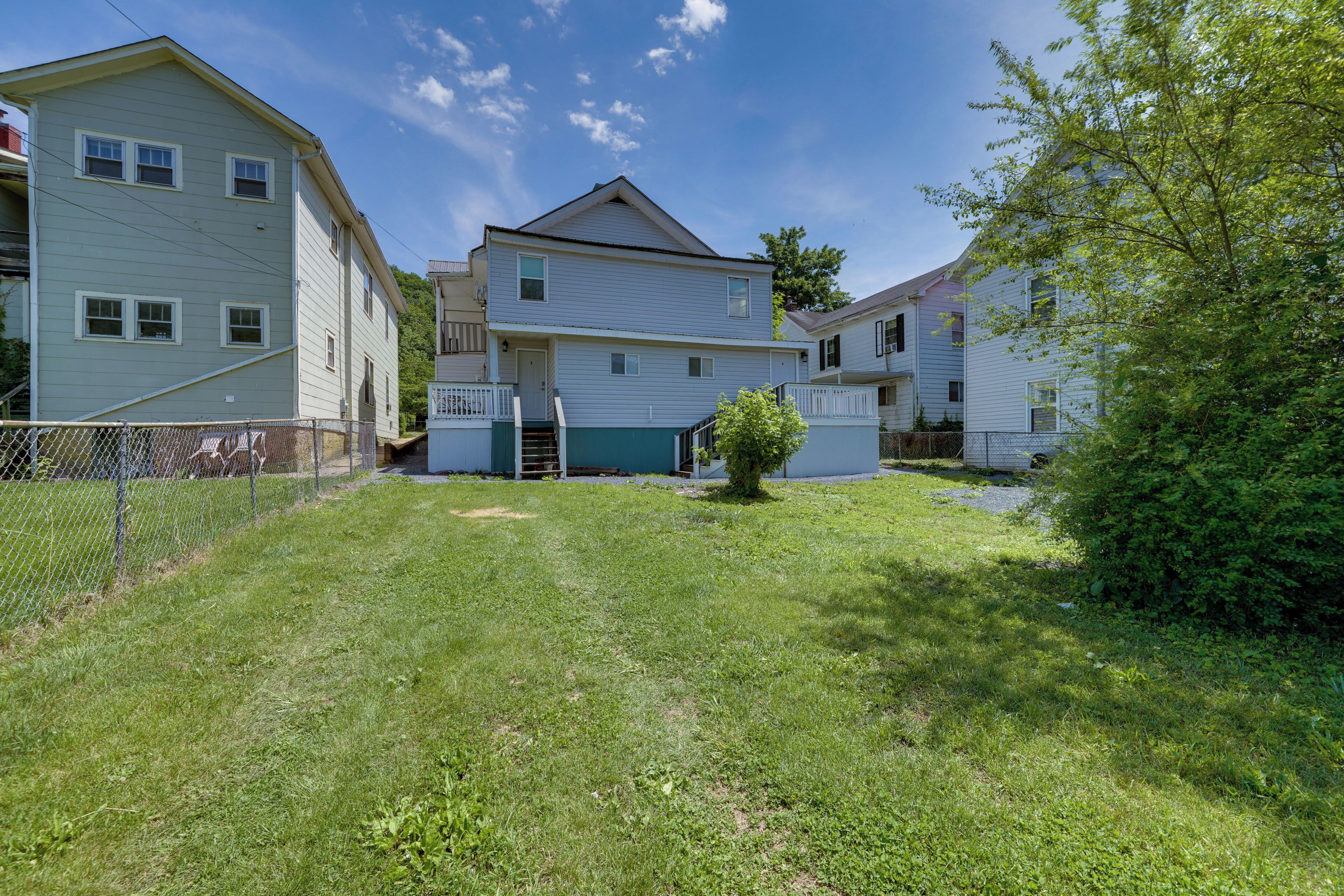 A residential area with two-story houses, a fenced yard, and a small tree.