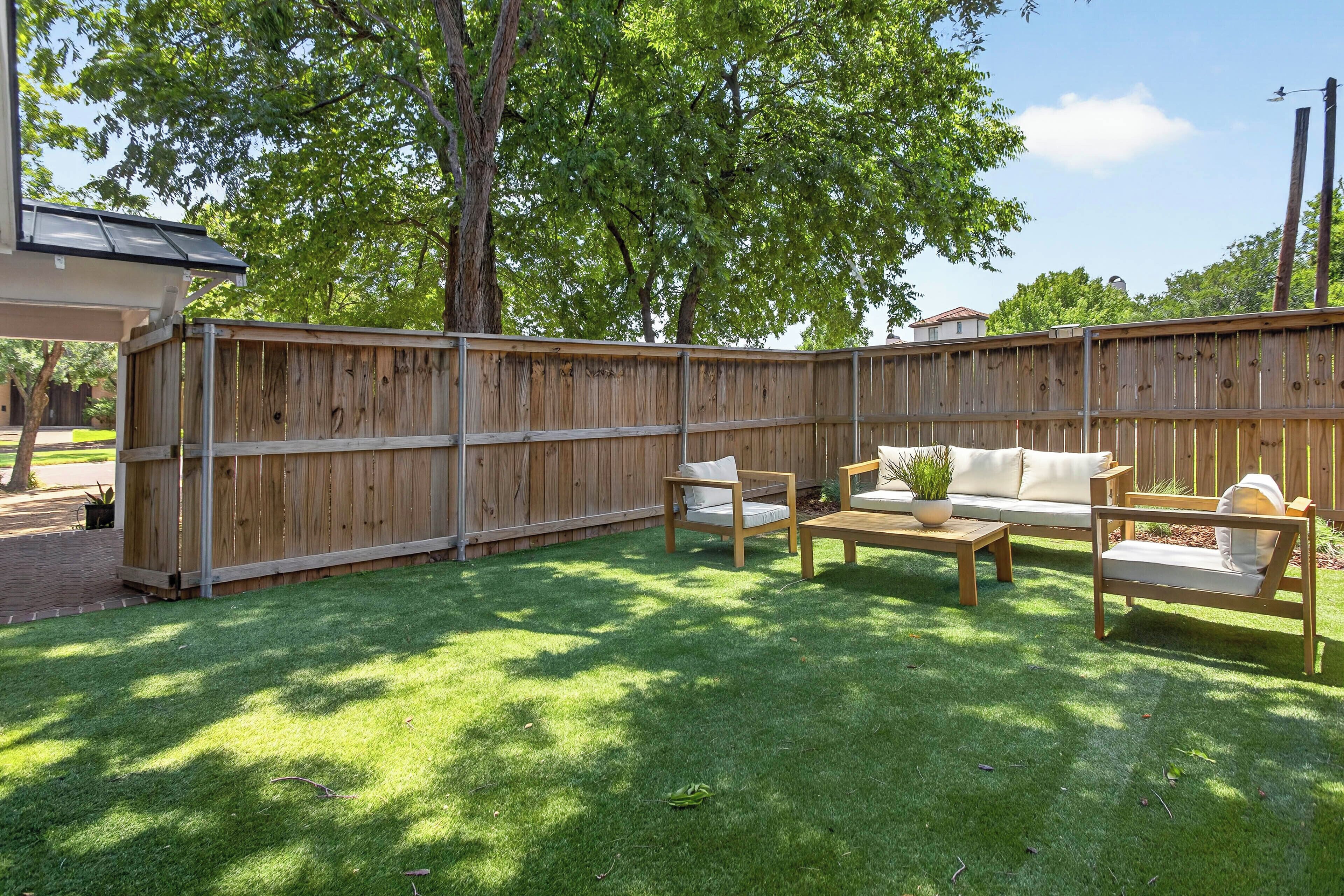 A fenced backyard with a wooden deck, a sofa, and a coffee table.