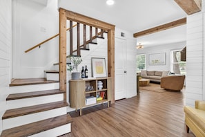 Eine Treppe führt in ein Wohnzimmer mit Holzboden, einer Couch und einem Couchtisch.