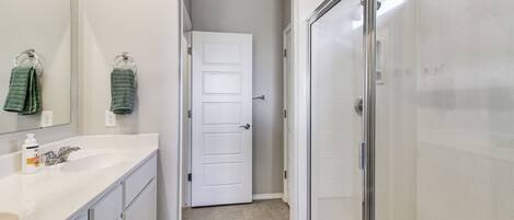 A bathroom with a white sink, mirror, and glass shower enclosure.